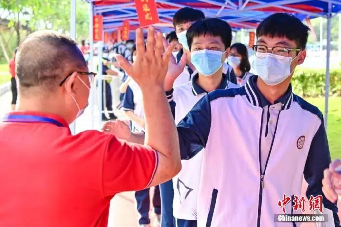 6月7日，广东省广州市南沙一中考点，老师与考生击掌为考生加油。  中新社记者 陈骥旻 摄