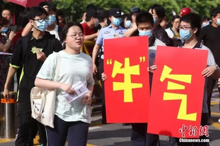 6月7日，江苏省南京市雨花台中学高考考点前，高二的学生手举“牛气冲天”“牛转乾坤”字样为考生加油鼓劲。中新社记者 泱波 摄